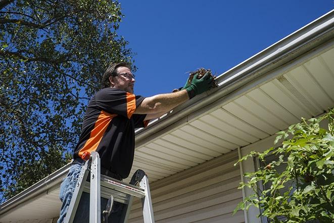 a handyman adjusting a gutter to direct rainwater away from a building in Oviedo, FL